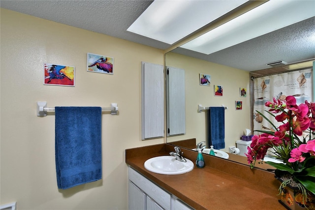 bathroom with vanity, a textured ceiling, a shower with curtain, and toilet