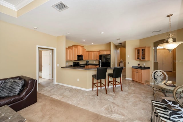 kitchen featuring kitchen peninsula, a breakfast bar, ornamental molding, black appliances, and pendant lighting