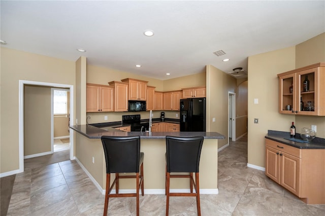 kitchen with black appliances, sink, a kitchen bar, light brown cabinetry, and kitchen peninsula