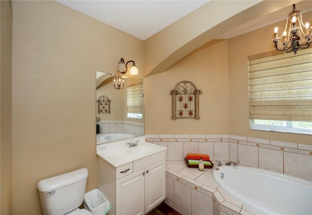 bathroom with vanity, an inviting chandelier, toilet, and tiled tub