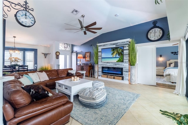 living room with light tile patterned flooring, lofted ceiling, a fireplace, ceiling fan with notable chandelier, and a barn door