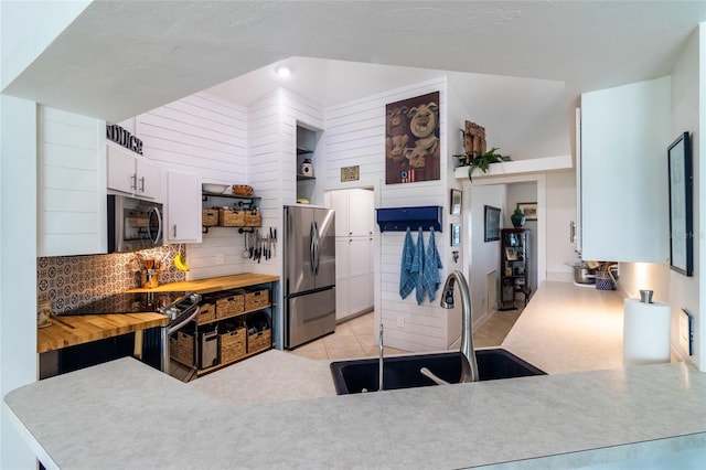 kitchen with light tile patterned flooring, white cabinetry, sink, and stainless steel appliances