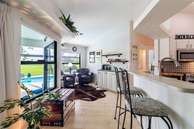 kitchen with light tile patterned floors, tasteful backsplash, and white cabinetry