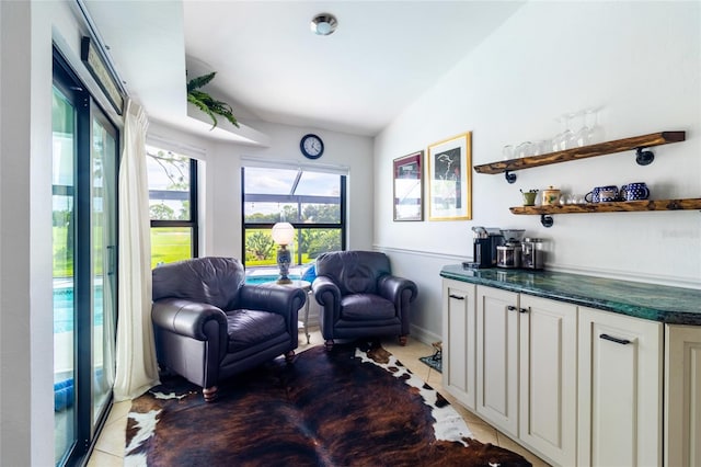 living area featuring bar, lofted ceiling, and tile patterned flooring