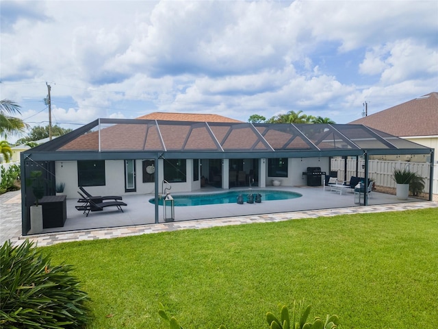 rear view of house featuring a lanai, a lawn, and a patio area