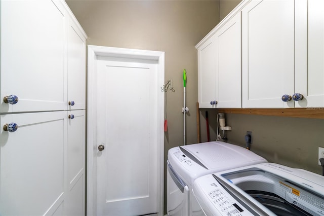 clothes washing area with washer and clothes dryer and cabinets