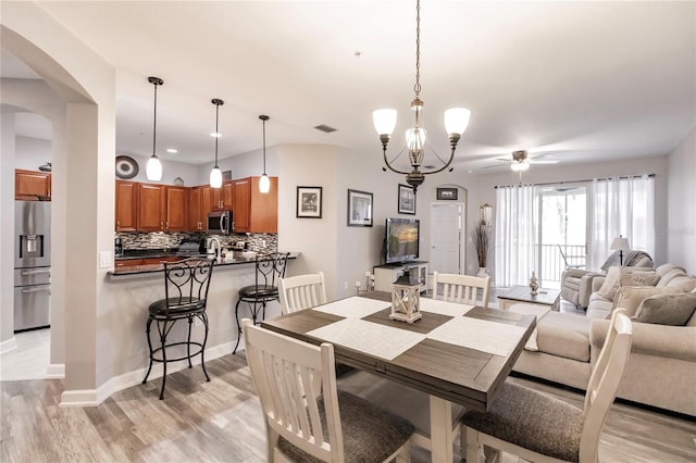 dining room featuring sink, ceiling fan with notable chandelier, and light hardwood / wood-style floors