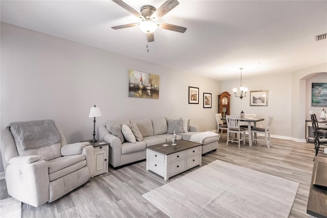 living room with ceiling fan with notable chandelier and light hardwood / wood-style floors