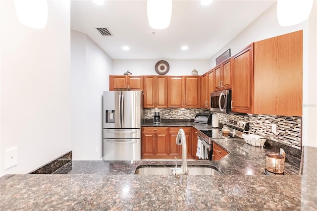 kitchen featuring dark stone countertops, stainless steel appliances, sink, and tasteful backsplash