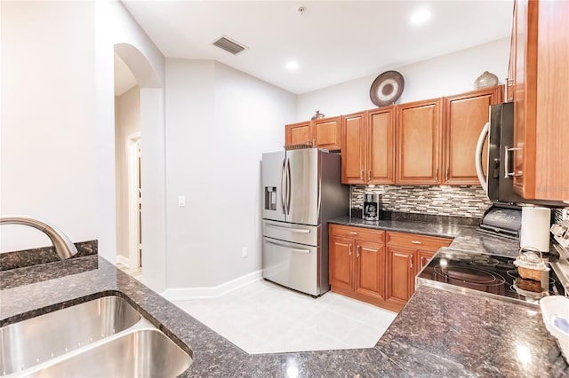 kitchen featuring tasteful backsplash, dark stone countertops, appliances with stainless steel finishes, and sink