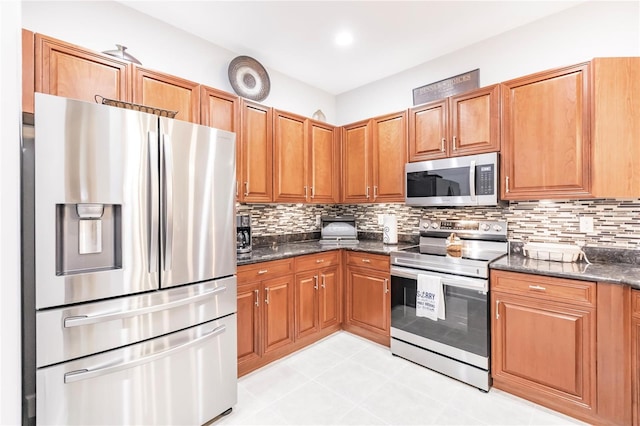 kitchen featuring dark stone countertops, appliances with stainless steel finishes, light tile patterned floors, and decorative backsplash