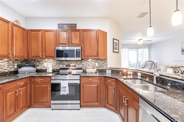 kitchen with stainless steel appliances, light tile patterned flooring, decorative light fixtures, and sink