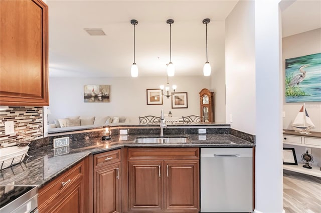 kitchen featuring appliances with stainless steel finishes, dark stone countertops, decorative light fixtures, and sink