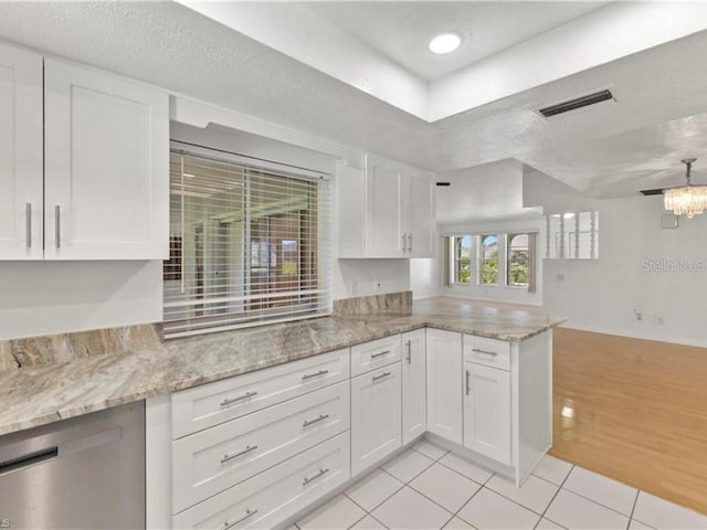 kitchen featuring kitchen peninsula, light tile patterned flooring, white cabinetry, light stone counters, and a textured ceiling