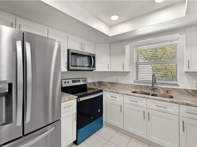 kitchen featuring stainless steel appliances, light stone countertops, sink, and white cabinets