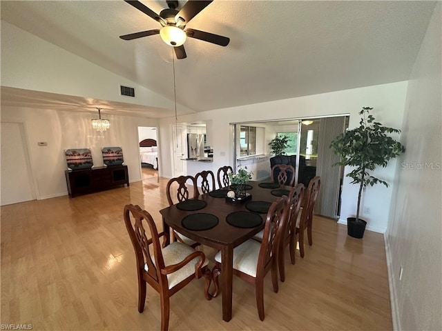 dining space featuring vaulted ceiling, light wood-type flooring, and ceiling fan with notable chandelier