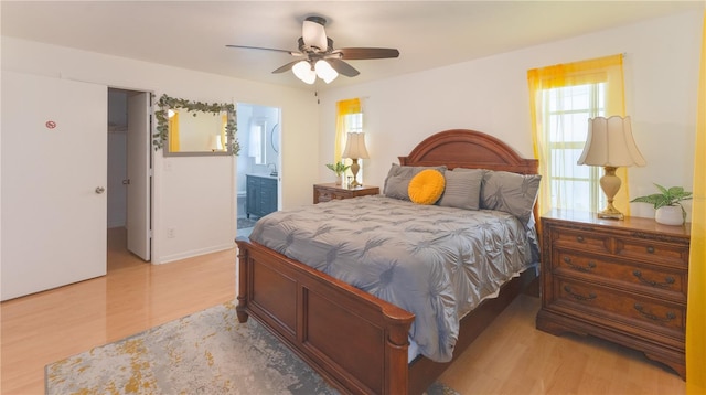 bedroom with connected bathroom, ceiling fan, and light wood-type flooring