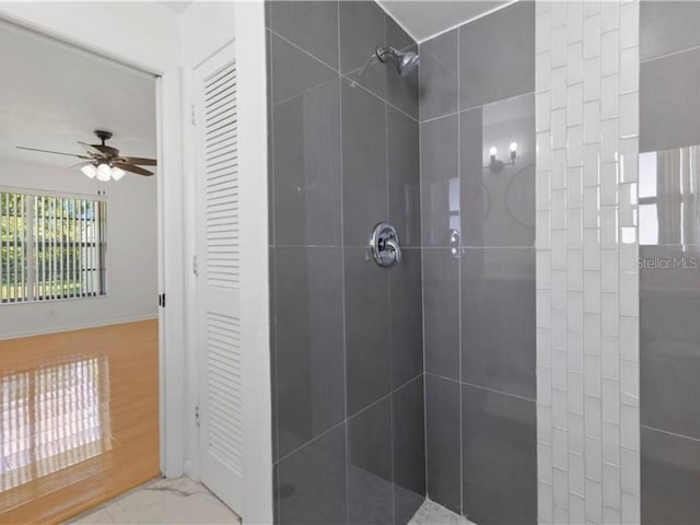 bathroom with ceiling fan and tiled shower