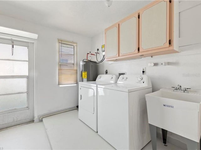 laundry room with sink, washing machine and dryer, cabinets, and water heater