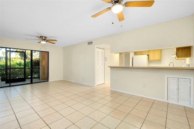 unfurnished living room featuring ceiling fan, light tile patterned flooring, and sink