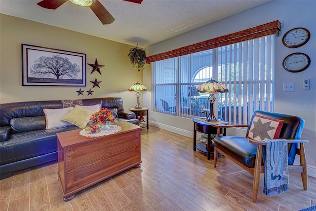 living room with ceiling fan, a textured ceiling, and light hardwood / wood-style floors