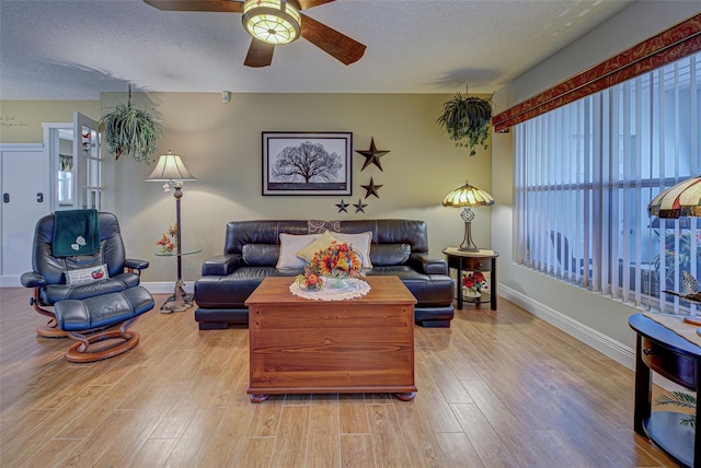 living room with ceiling fan, a textured ceiling, and light wood-type flooring