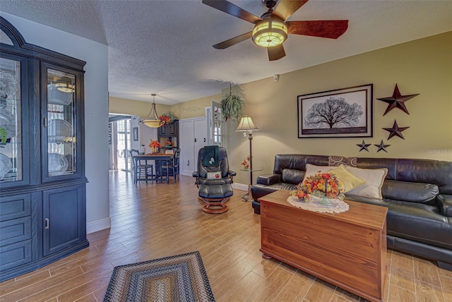 living room with a textured ceiling, light hardwood / wood-style floors, and ceiling fan