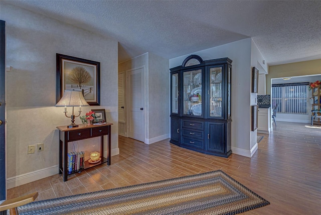 corridor featuring a textured ceiling and light hardwood / wood-style flooring