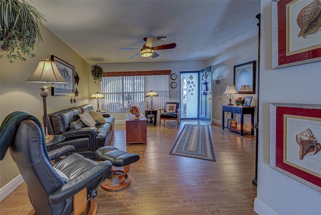 living room with ceiling fan, a textured ceiling, and hardwood / wood-style floors