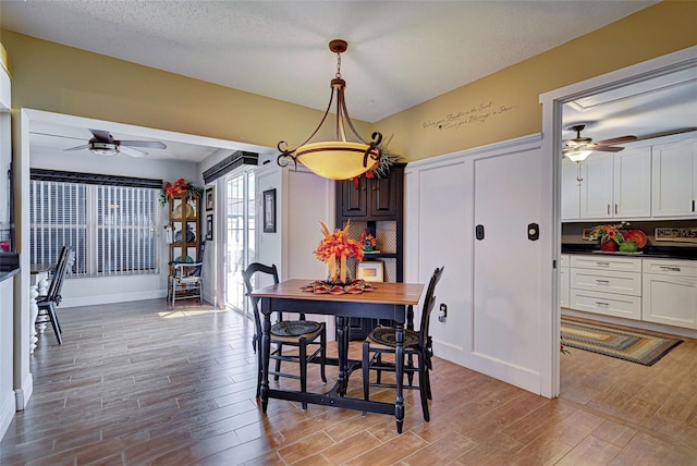 dining room with light wood-type flooring, a textured ceiling, and ceiling fan