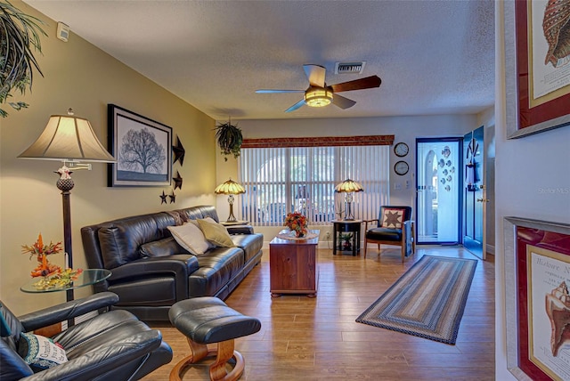 living room featuring a textured ceiling, hardwood / wood-style flooring, and ceiling fan