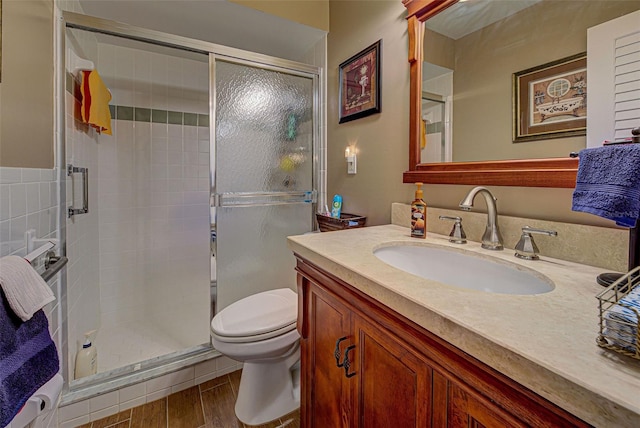 bathroom featuring hardwood / wood-style floors, a shower with door, vanity, and toilet