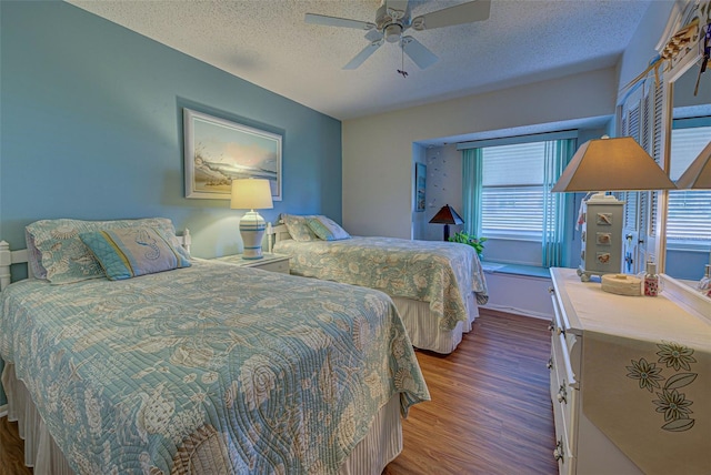 bedroom with ceiling fan, a textured ceiling, and dark hardwood / wood-style floors