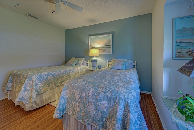 bedroom with ceiling fan, hardwood / wood-style flooring, and a textured ceiling