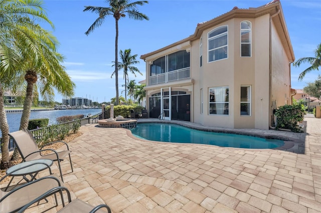 view of pool featuring an in ground hot tub, a water view, a patio area, and a sunroom