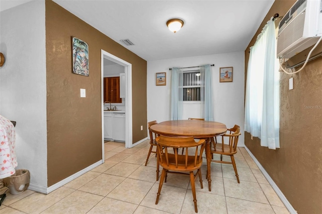 dining room with an AC wall unit, light tile patterned floors, and sink