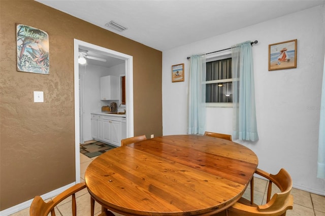 dining area with light tile patterned flooring, sink, and ceiling fan