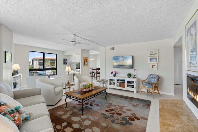 living room with ceiling fan, a textured ceiling, and light tile patterned floors