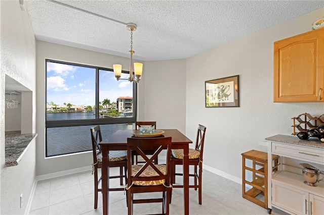 dining space featuring a textured ceiling, a water view, an inviting chandelier, and light tile patterned floors