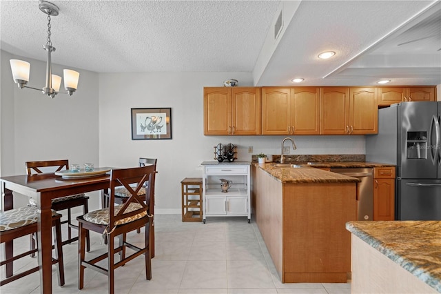 kitchen featuring a textured ceiling, sink, a notable chandelier, appliances with stainless steel finishes, and decorative light fixtures