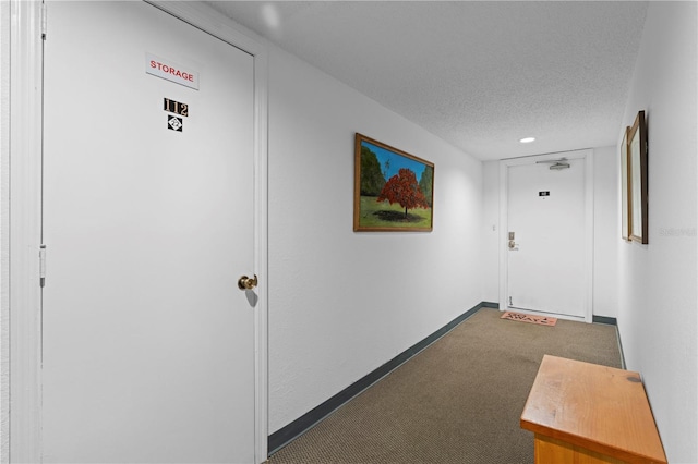 corridor featuring a textured ceiling and dark colored carpet