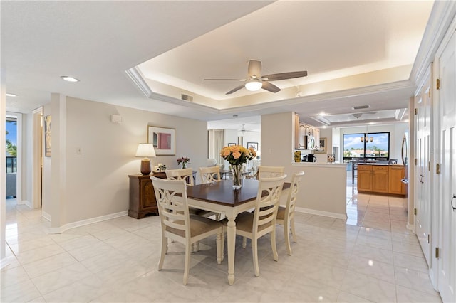 tiled dining room featuring a raised ceiling and ceiling fan