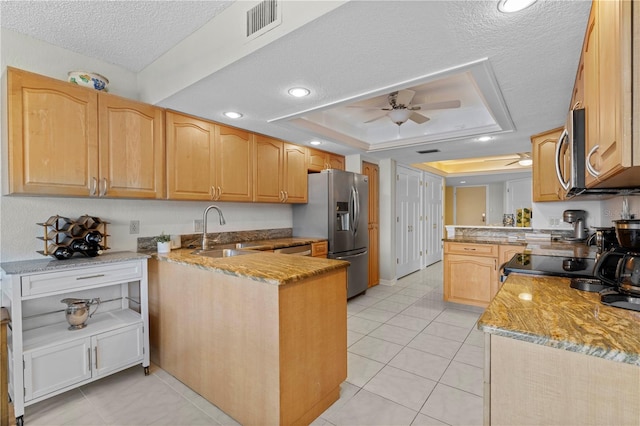 kitchen featuring a tray ceiling, a textured ceiling, sink, kitchen peninsula, and appliances with stainless steel finishes