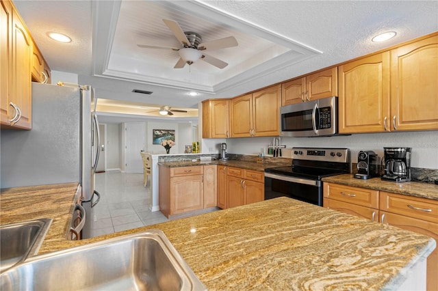 kitchen with a textured ceiling, a raised ceiling, kitchen peninsula, and stainless steel appliances