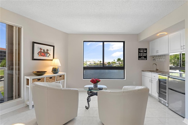 living room featuring a textured ceiling, sink, light tile patterned floors, and wine cooler