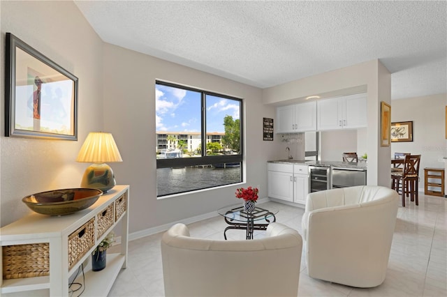 living room featuring a textured ceiling, beverage cooler, and sink