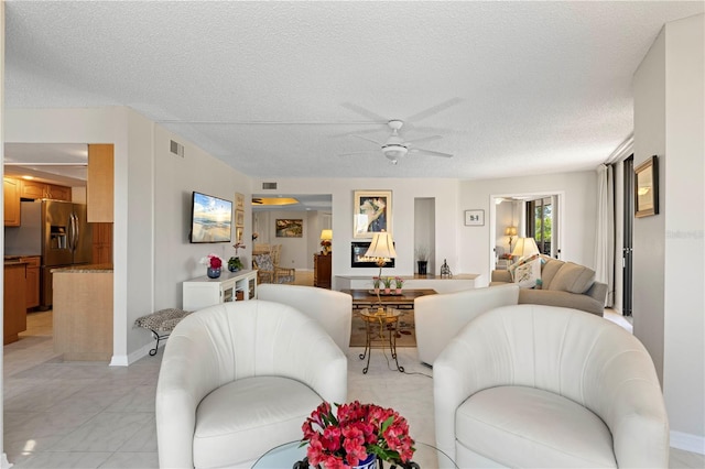 tiled living room with a textured ceiling and ceiling fan