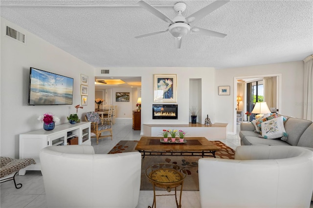 living room with light tile patterned floors, a textured ceiling, and ceiling fan