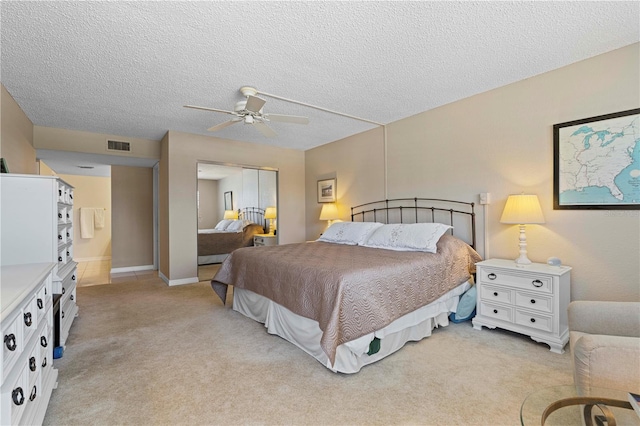 bedroom featuring light carpet, ceiling fan, and a textured ceiling