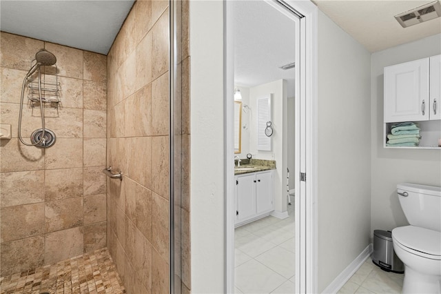 bathroom featuring vanity, a textured ceiling, a tile shower, tile patterned floors, and toilet